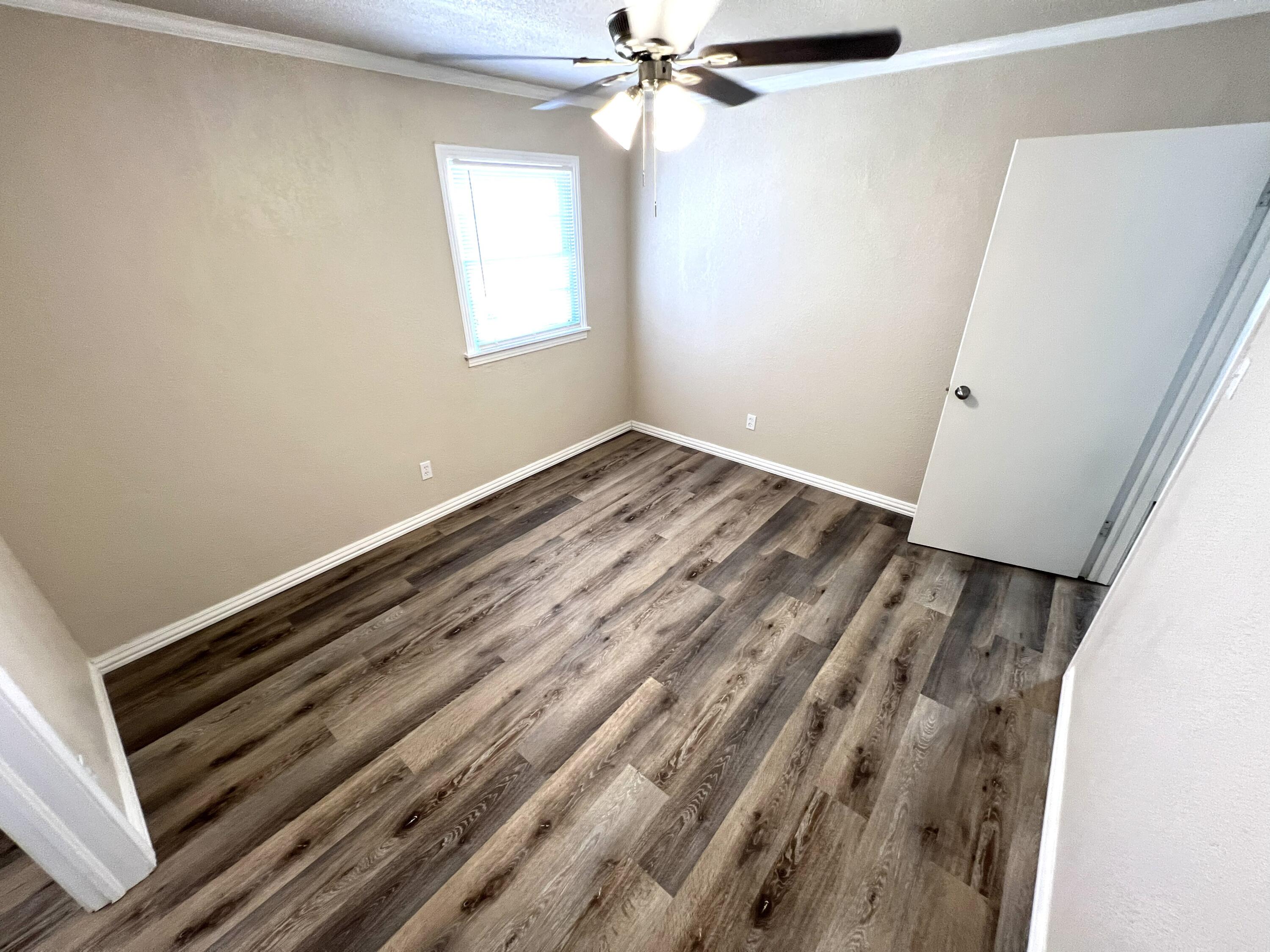 1910 64th Street Lubbock, TX 79412 - Photo 16 of 18 a view of an empty room with wooden floor and a window