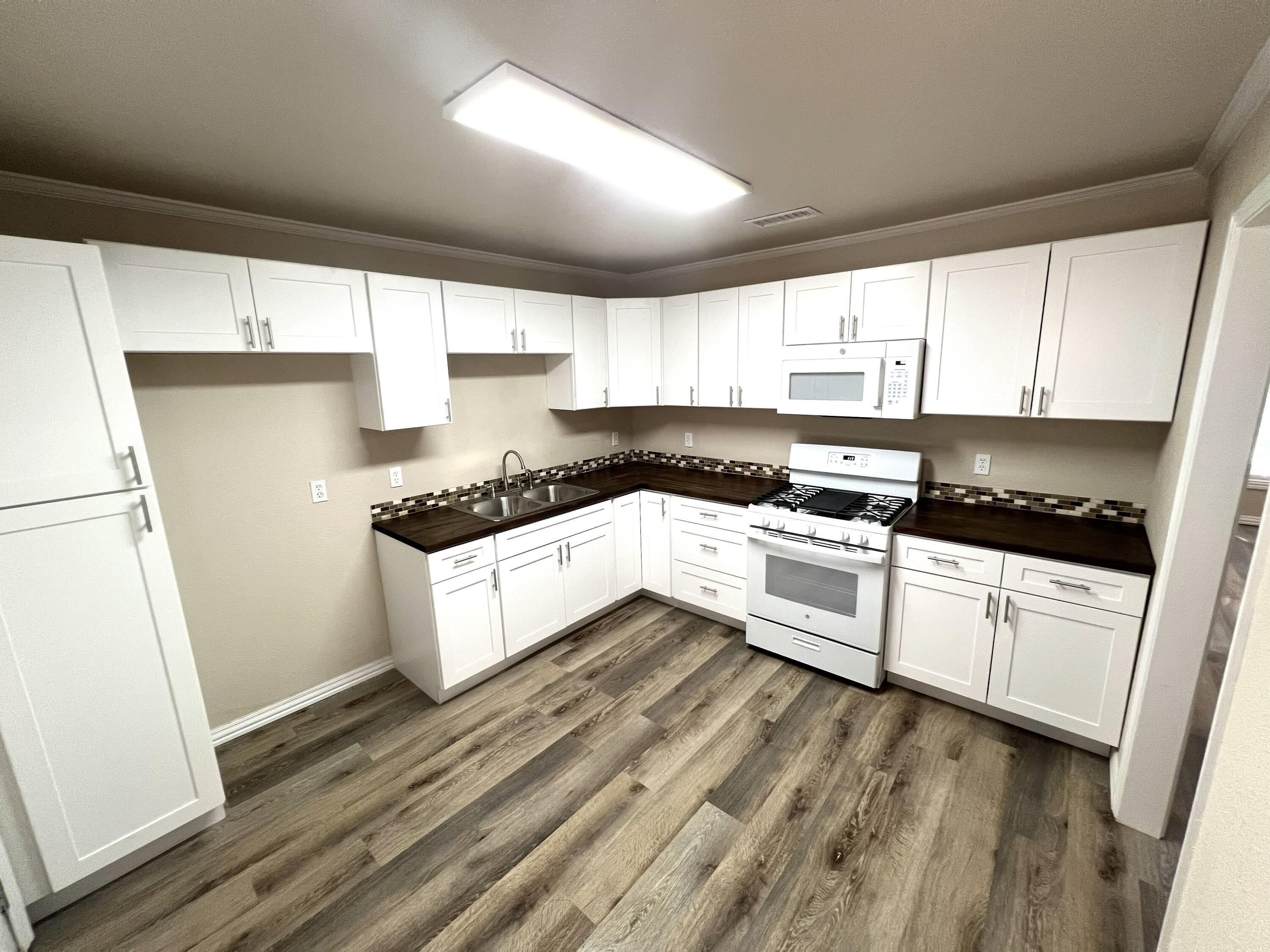 1910 64th Street Lubbock, TX 79412 - Photo 6 of 18 a kitchen with granite countertop white cabinets and white appliances