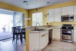 2120 Northwest Marsh Rabbit Lane Jensen Beach, FL 34957 - Photo 17 of 34 a kitchen with stainless steel appliances granite countertop a stove a sink and a microwave