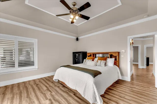 a bedroom with a bed and a large window with wooden floor