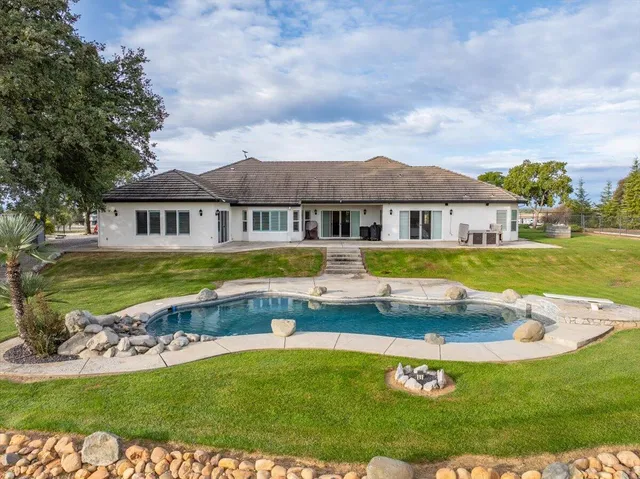 a view of a house with swimming pool and a yard