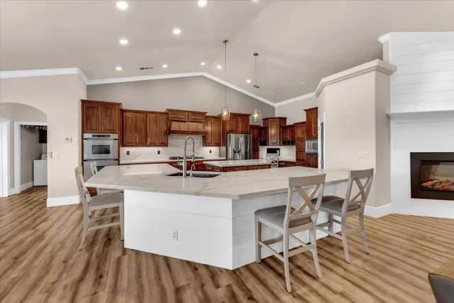 a kitchen with stainless steel appliances kitchen island granite countertop a table chairs and a refrigerator