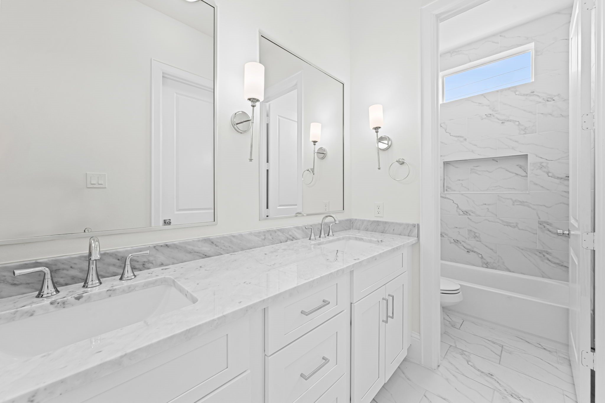 533 West 27th Street Houston, TX 77008 - Photo 19 of 22 Secondary bath features Carrara marble countertops, shaker-style cabinetry, and marble-look tile surrounding the tub and shower.