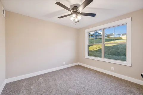 an empty room with a window and a fan