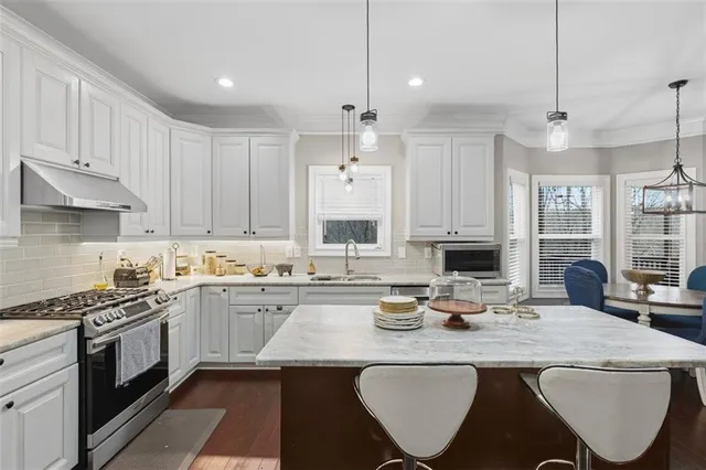 a kitchen with sink a stove and chairs with wooden floor