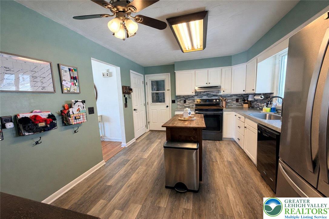 1060 Arbor Lane Slatington, PA 18080 - Photo 12 of 46 a kitchen with stainless steel appliances a stove a refrigerator a sink dishwasher and a dining table with wooden floor