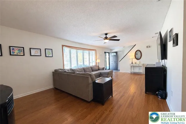 a living room with couches and kitchen view with wooden floor