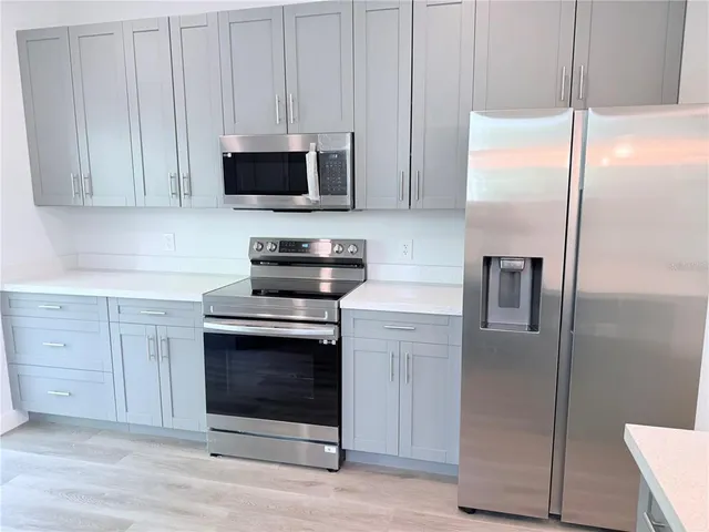 a kitchen with stainless steel appliances granite countertop a refrigerator a stove and a microwave with wooden floor