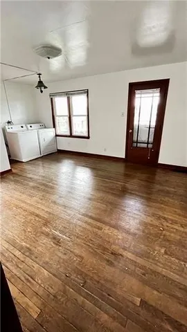 a view of an empty room with window and wooden floor
