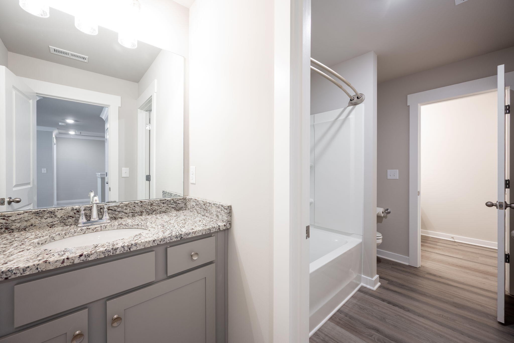 7401 McDaniel Lane Ooltewah, TN 37363 - Photo 33 of 44 a bathroom with a granite countertop sink a mirror and a bathtub