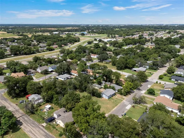 an aerial view of residential houses with outdoor space and trees