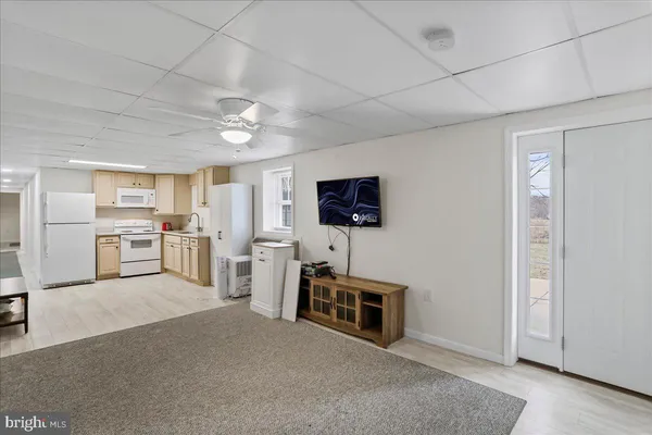 a living room with furniture a flat screen tv and kitchen view
