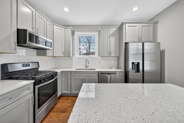 a kitchen with stainless steel appliances granite countertop a stove a sink and a refrigerator