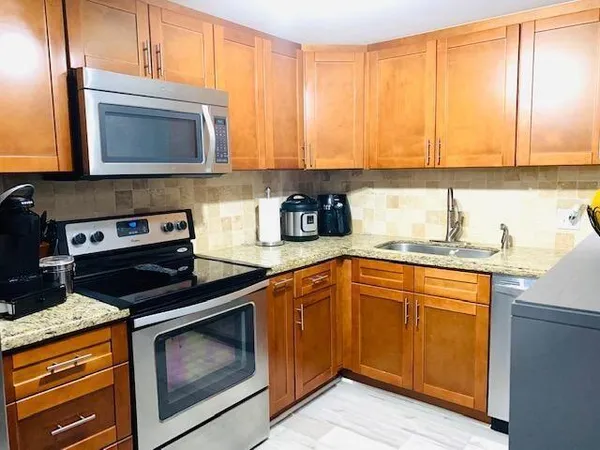 a kitchen with granite countertop cabinets stainless steel appliances and a sink