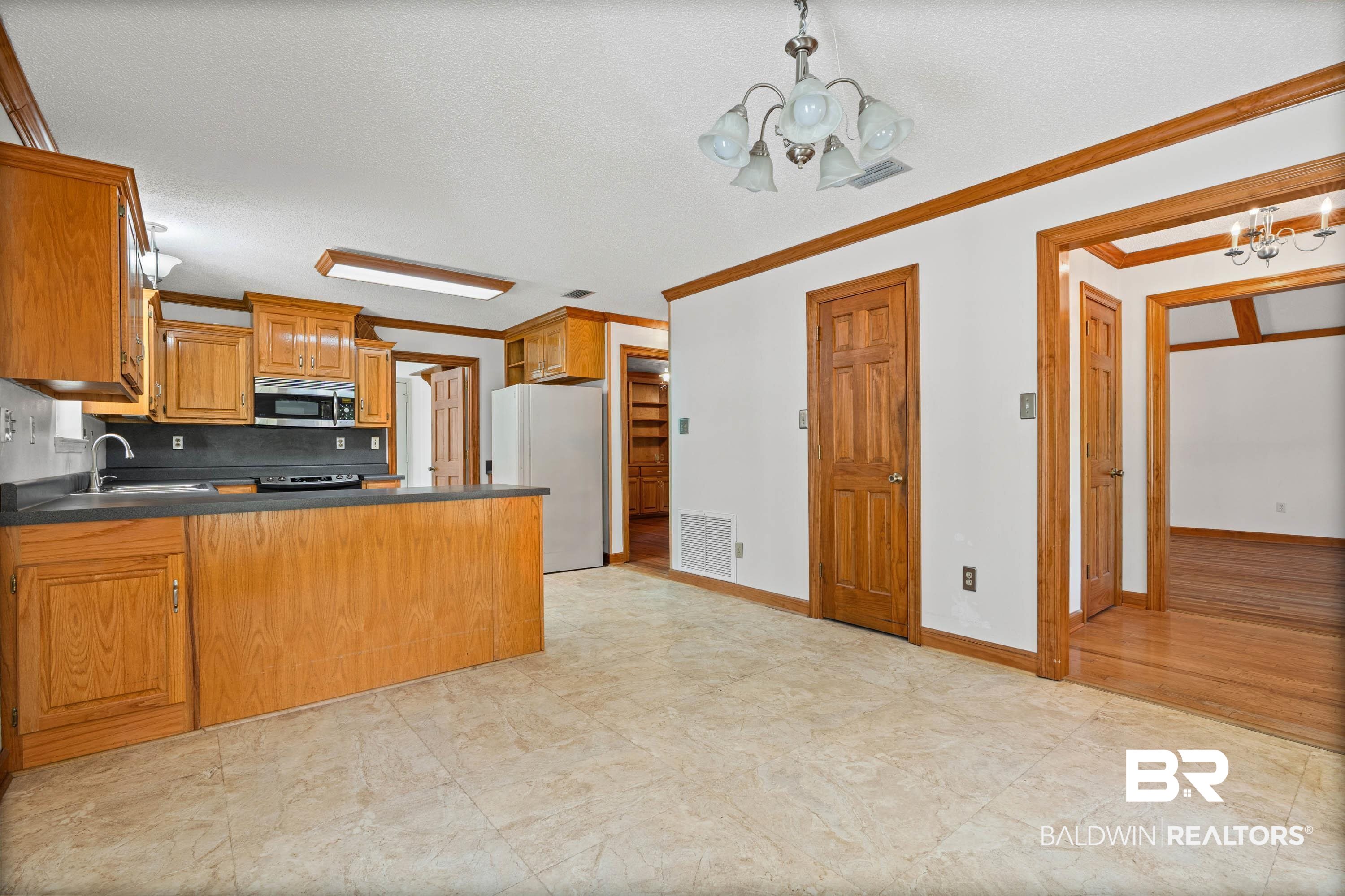 10140 Lakeview Road Bay Minette, AL 36507 - Photo 10 of 35 Kitchen with dark countertops, hanging lights, wood finish cabinets, freestanding refrigerator, and a peninsula