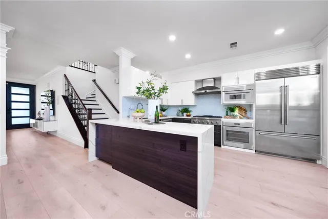 a kitchen with kitchen island a counter top space a sink stainless steel appliances and cabinets