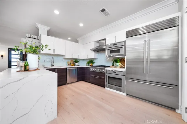 a kitchen with stainless steel appliances kitchen island granite countertop a stove a sink and white cabinets