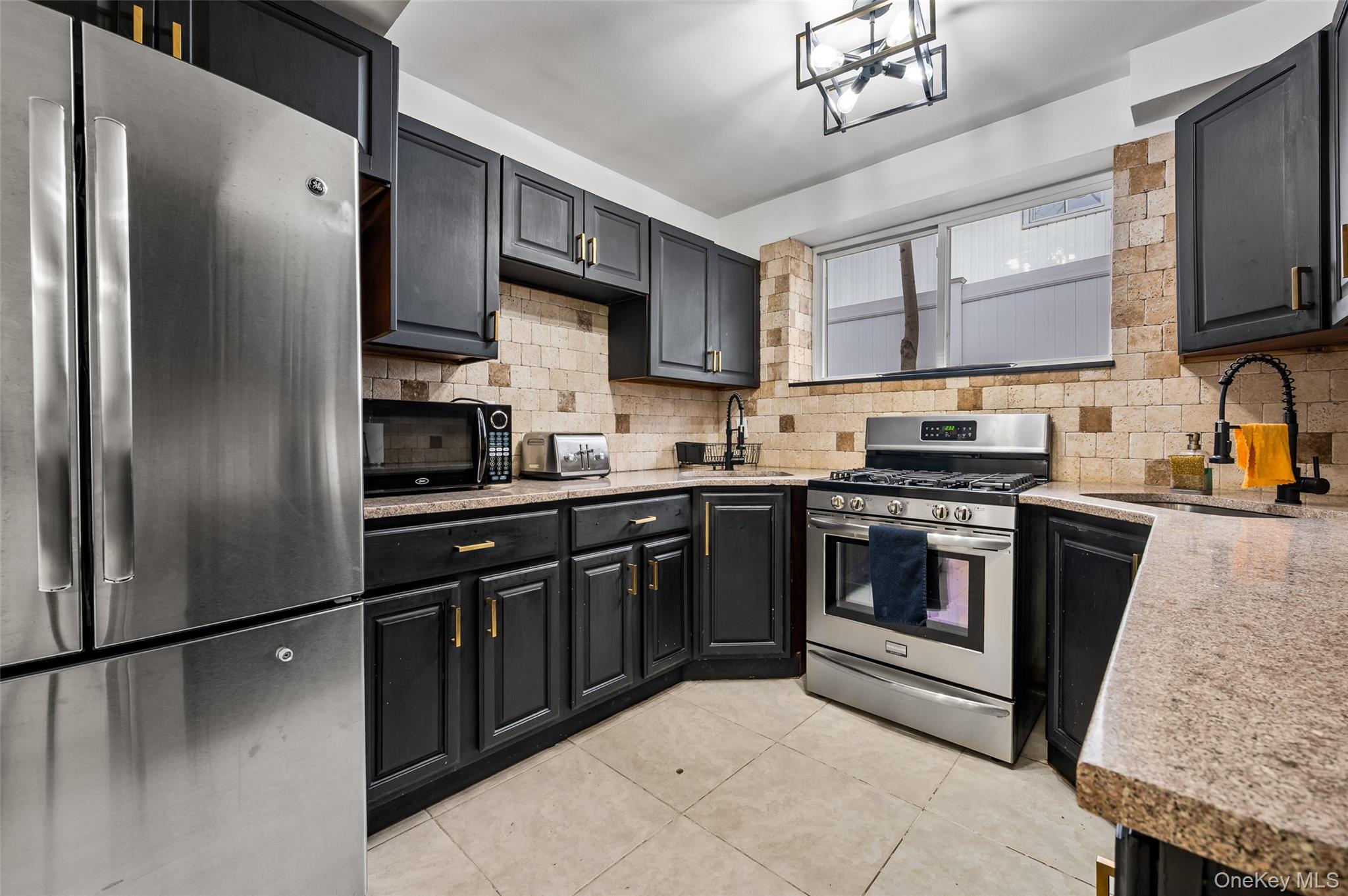 1016 Westwood Road Woodmere, NY 11598 - Photo 15 of 23 a kitchen with stainless steel appliances granite countertop a refrigerator a sink dishwasher a stove top oven a refrigerator with grey cabinets and wooden floor