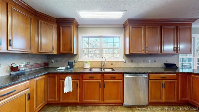 a kitchen with granite countertop wooden cabinets stainless steel appliances a sink and a window