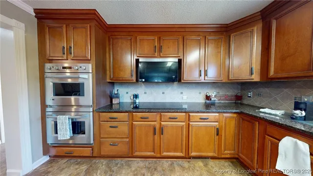 a kitchen with stainless steel appliances granite countertop wooden cabinets and a stove top oven