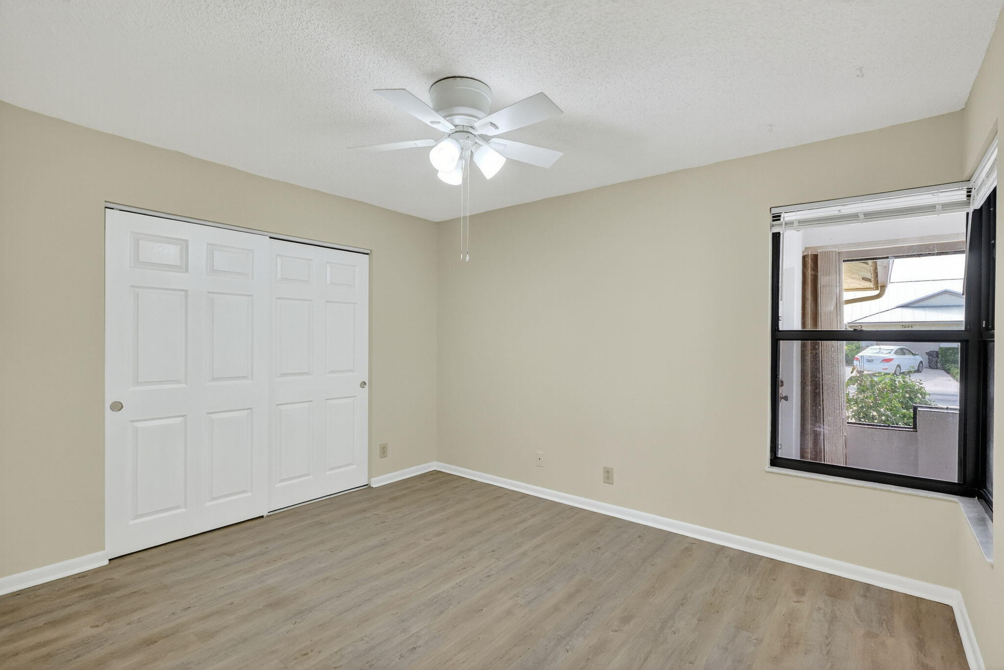 7643 Southeast Sugar Sand Circle Hobe Sound, FL 33455 - Photo 16 of 44 an empty room with wooden floor chandelier fan and windows