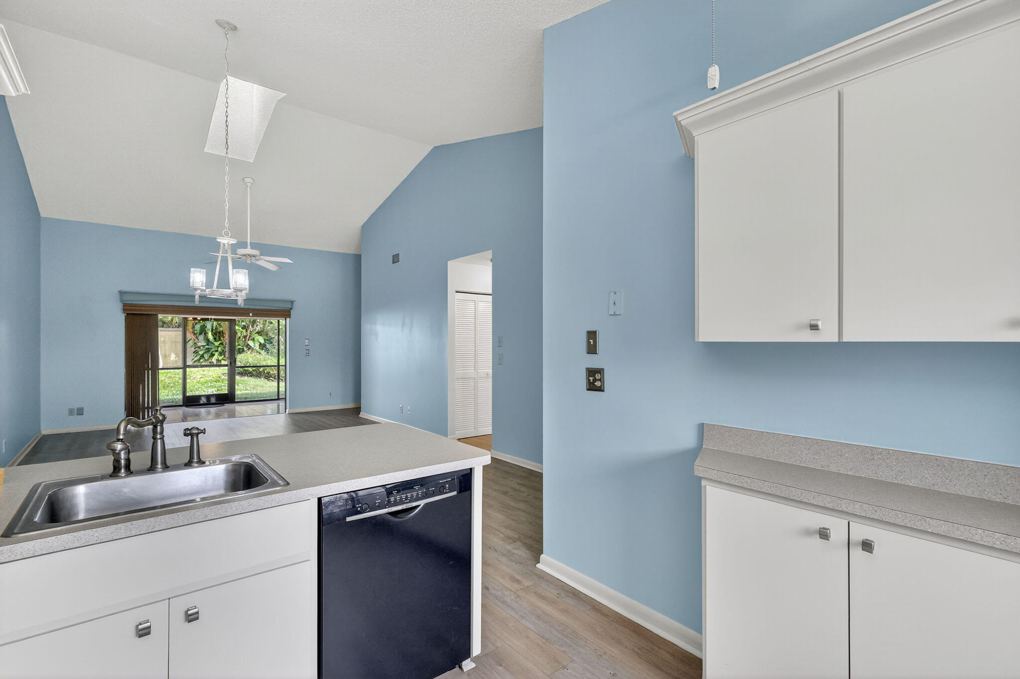 7643 Southeast Sugar Sand Circle Hobe Sound, FL 33455 - Photo 7 of 44 a kitchen with a sink dishwasher and white cabinets with wooden floor