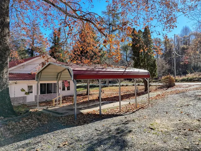 a view of a white house and a yard with wooden fence