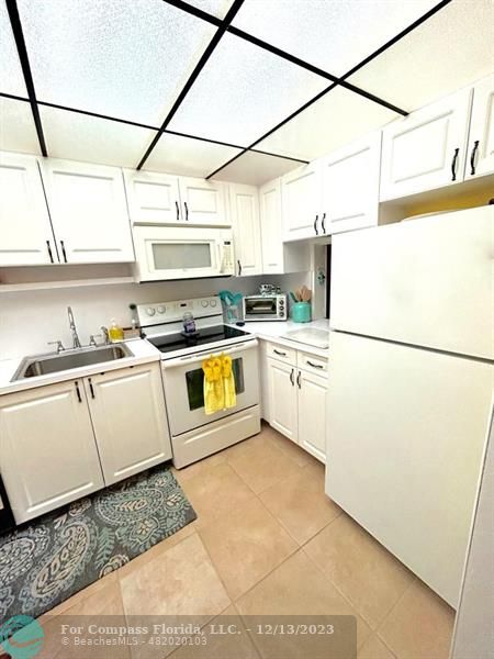 a kitchen with a refrigerator a stove a sink dishwasher and white cabinets