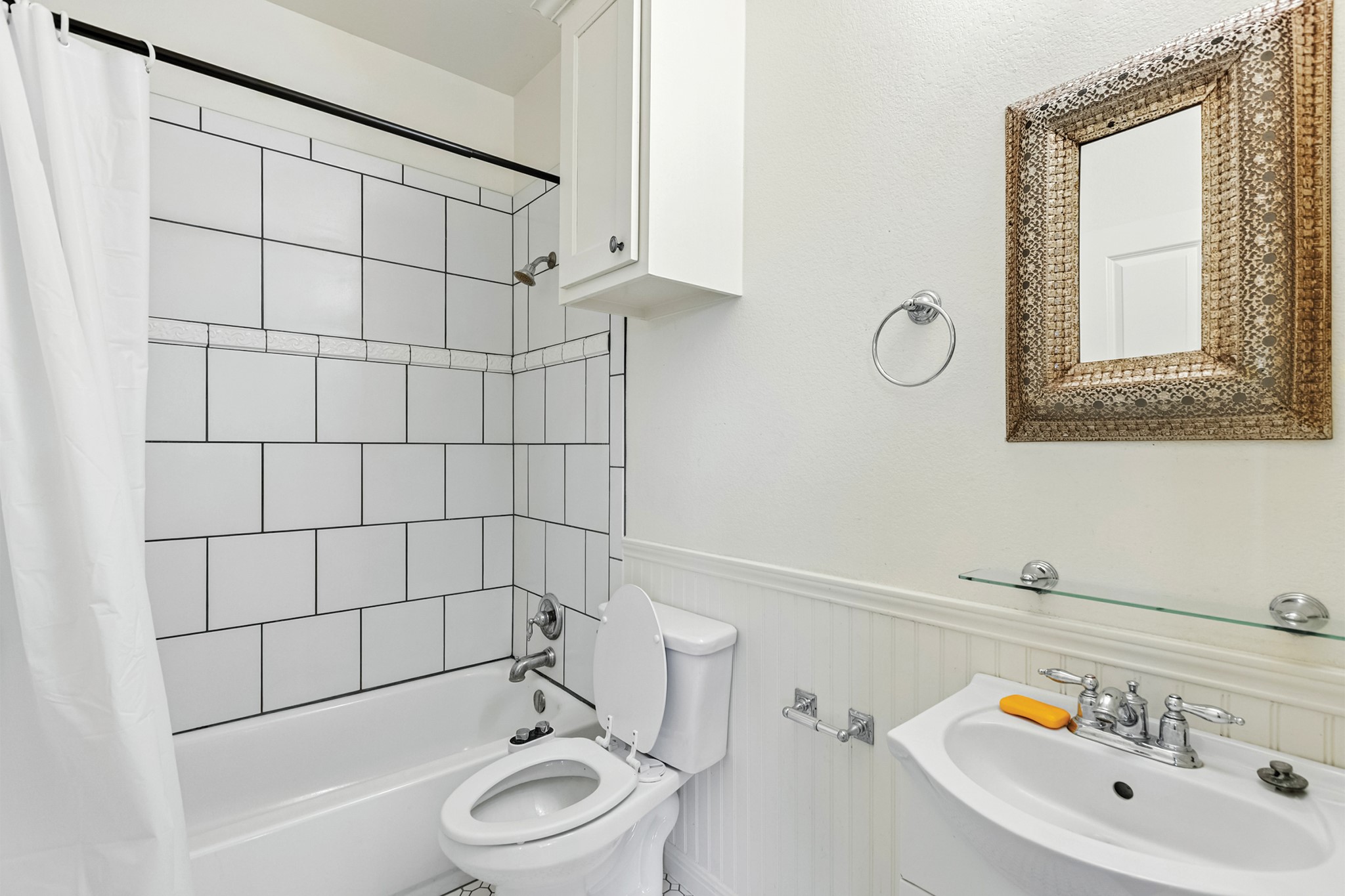 498 North County Line Road Elgin, TX 78621 - Photo 30 of 40 Bathroom featuring shower / bath combination with curtain and a wainscoted wall