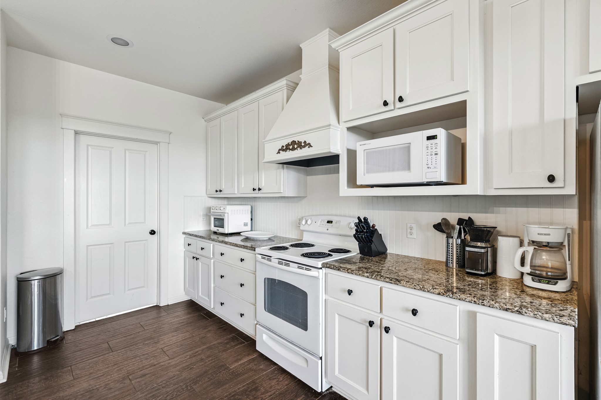 498 North County Line Road Elgin, TX 78621 - Photo 34 of 40 Kitchen with white appliances, white cabinets, dark wood finished floors, premium range hood, and dark stone countertops