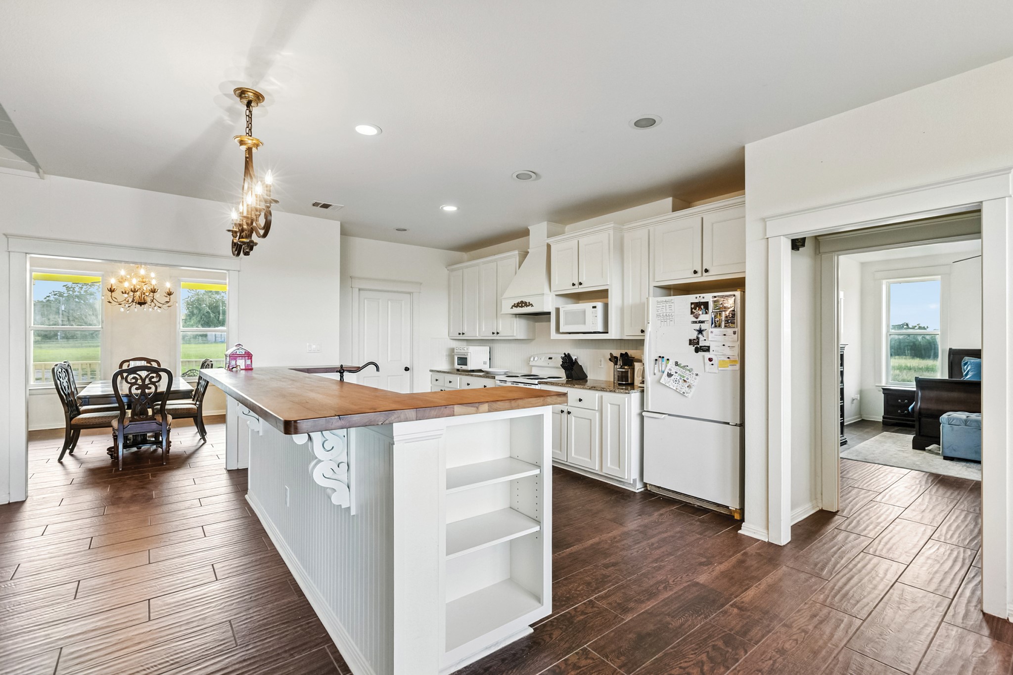498 North County Line Road Elgin, TX 78621 - Photo 35 of 40 Kitchen featuring white appliances, a center island with sink, white cabinetry, dark wood-style flooring, and recessed lighting
