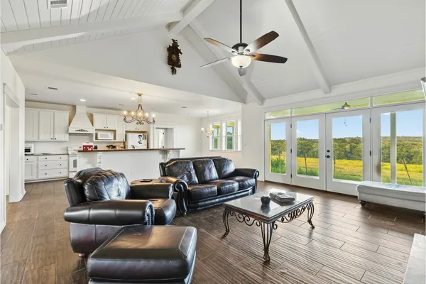 a living room with furniture and a large window with kitchen view