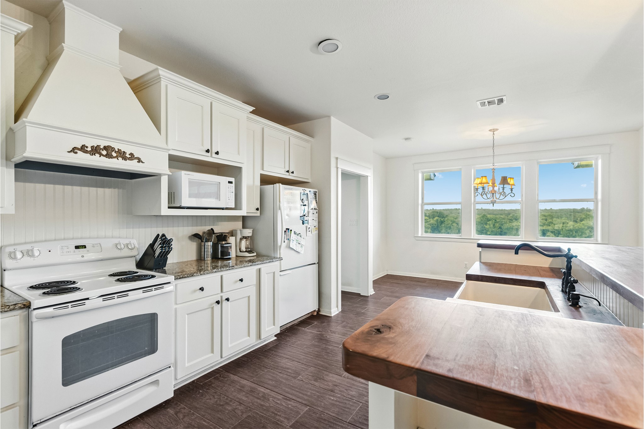 498 North County Line Road Elgin, TX 78621 - Photo 9 of 40 Kitchen featuring white appliances, pendant lighting, custom exhaust hood, dark wood-type flooring, and white cabinetry