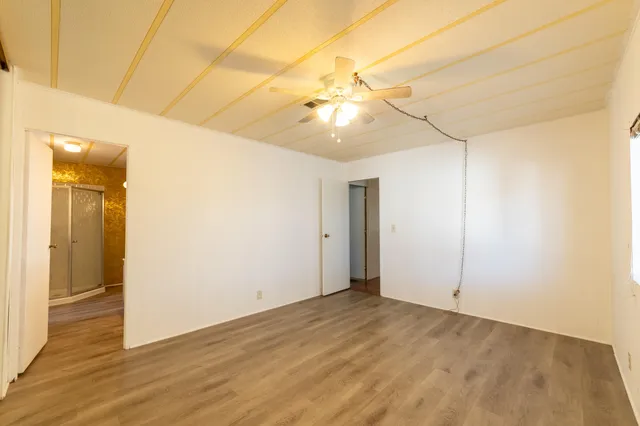 an empty room with wooden floor and fan