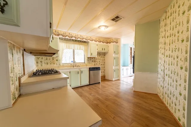 a large kitchen with kitchen island a large window a sink and stainless steel appliances