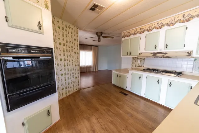 a kitchen with stainless steel appliances kitchen island granite countertop a stove a sink and white cabinets