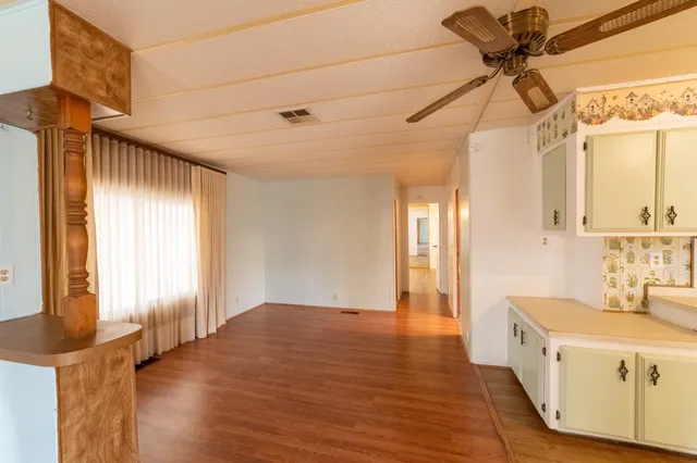 a hallway with a chandelier fan and wooden floor