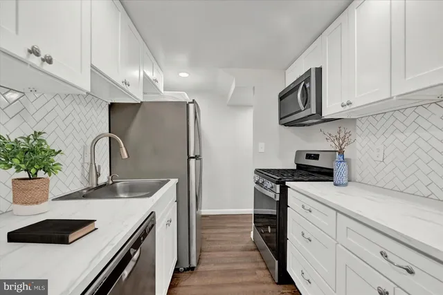 a kitchen with granite countertop a sink stainless steel appliances and cabinets