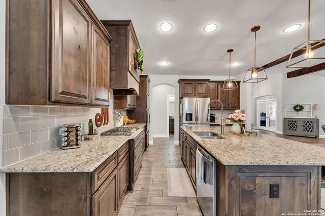 a kitchen with granite countertop a sink a counter top space stainless steel appliances and cabinets