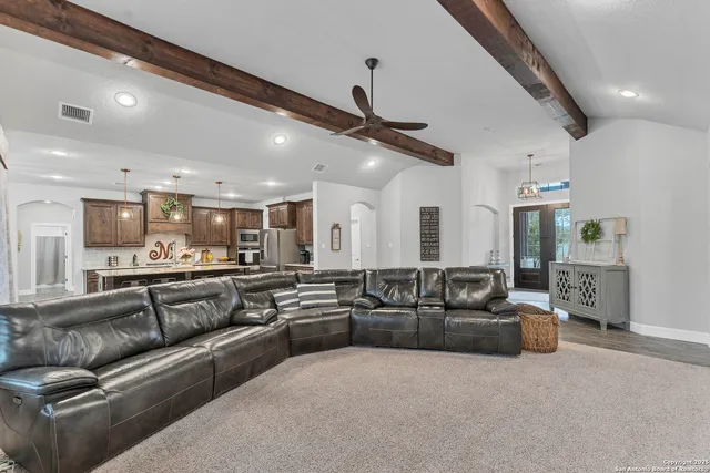 a living room with furniture kitchen view and a chandelier