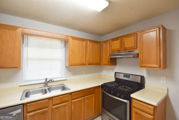 a kitchen with granite countertop a sink stove and cabinets