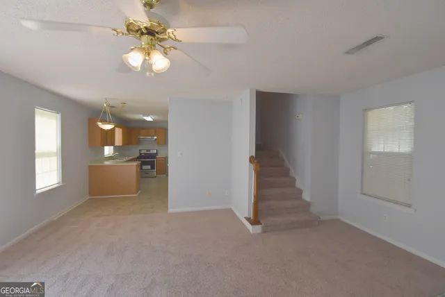 an empty room with windows and ceiling fan