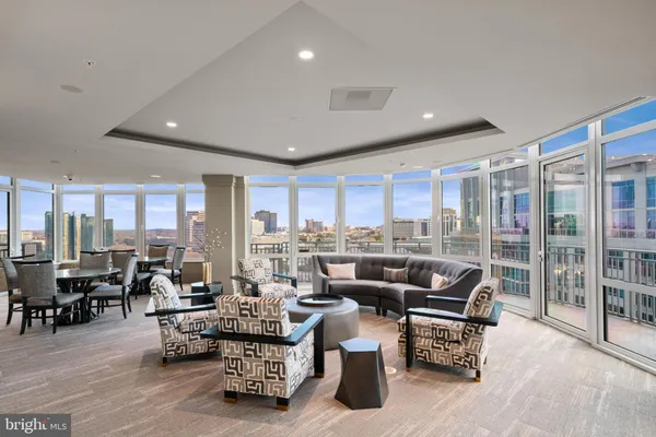 a living room with furniture large windows and wooden floor