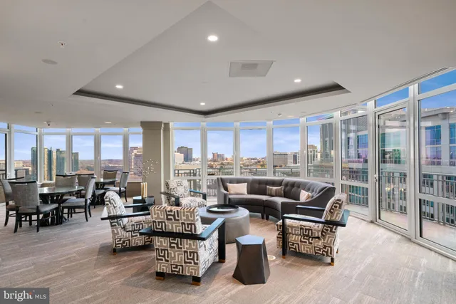 a living room with furniture large windows and wooden floor