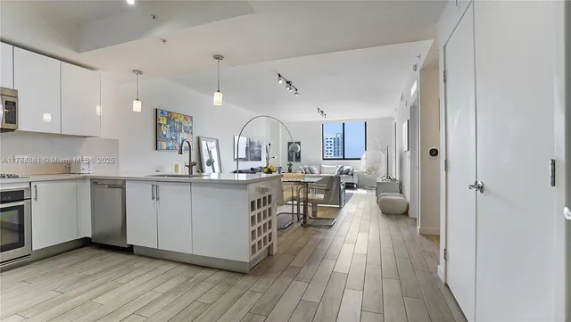 a large white kitchen with wooden floor and a sink