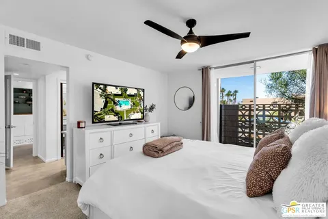 a bedroom with a bed a dresser and flat screen tv
