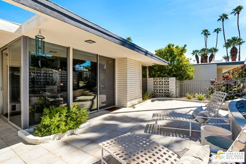 a patio with a table and chairs and potted plants