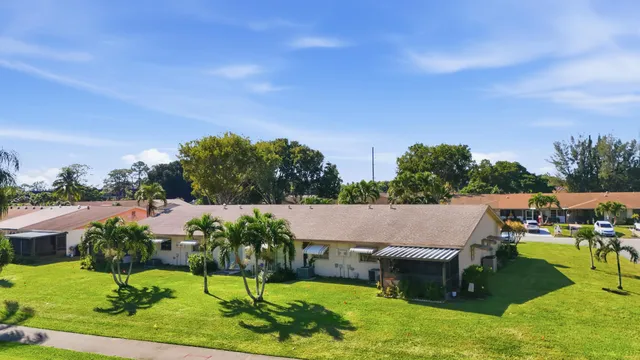 a view of a house with a yard and palm trees