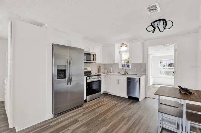 a kitchen with a refrigerator cabinets and wooden floor