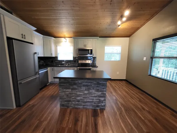 a kitchen with kitchen island a counter space a sink appliances and cabinets